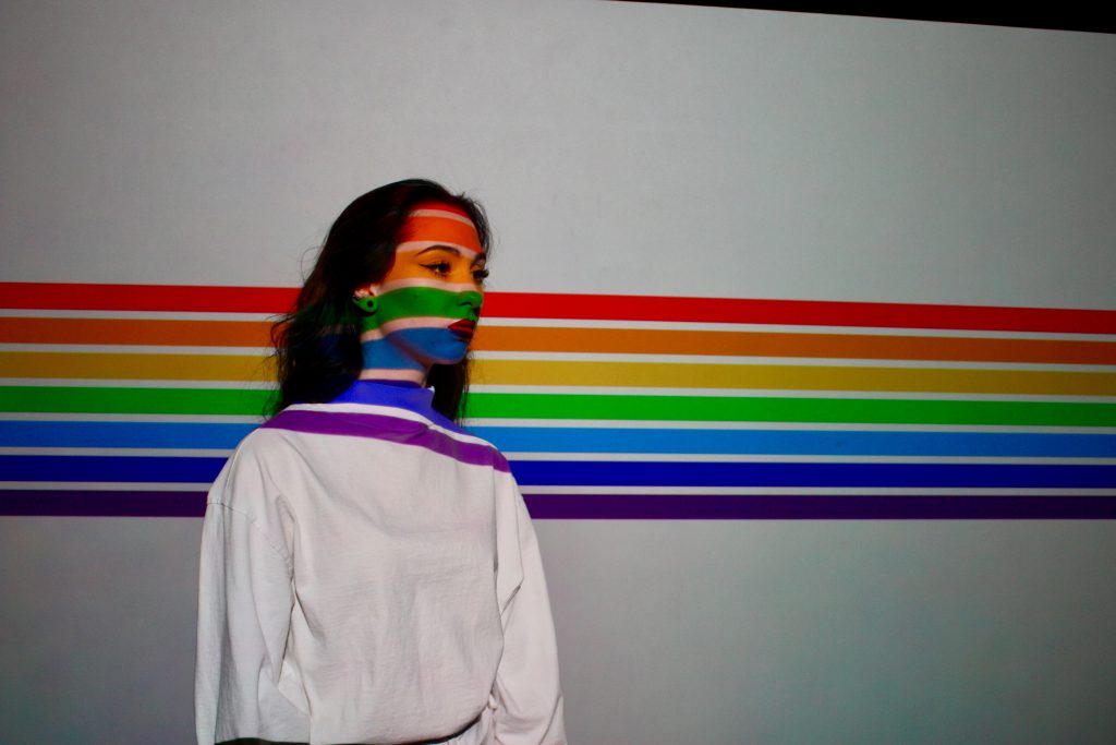 rainbow stripes painted on a wall and across a woman's face